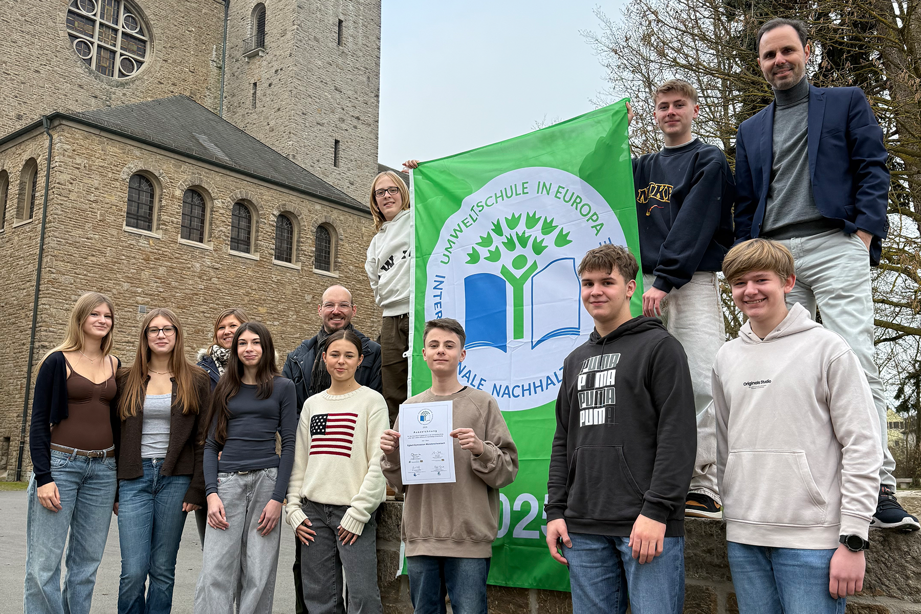 Schülergruppe und Schulleiter mit dem Logo der Umweltschule