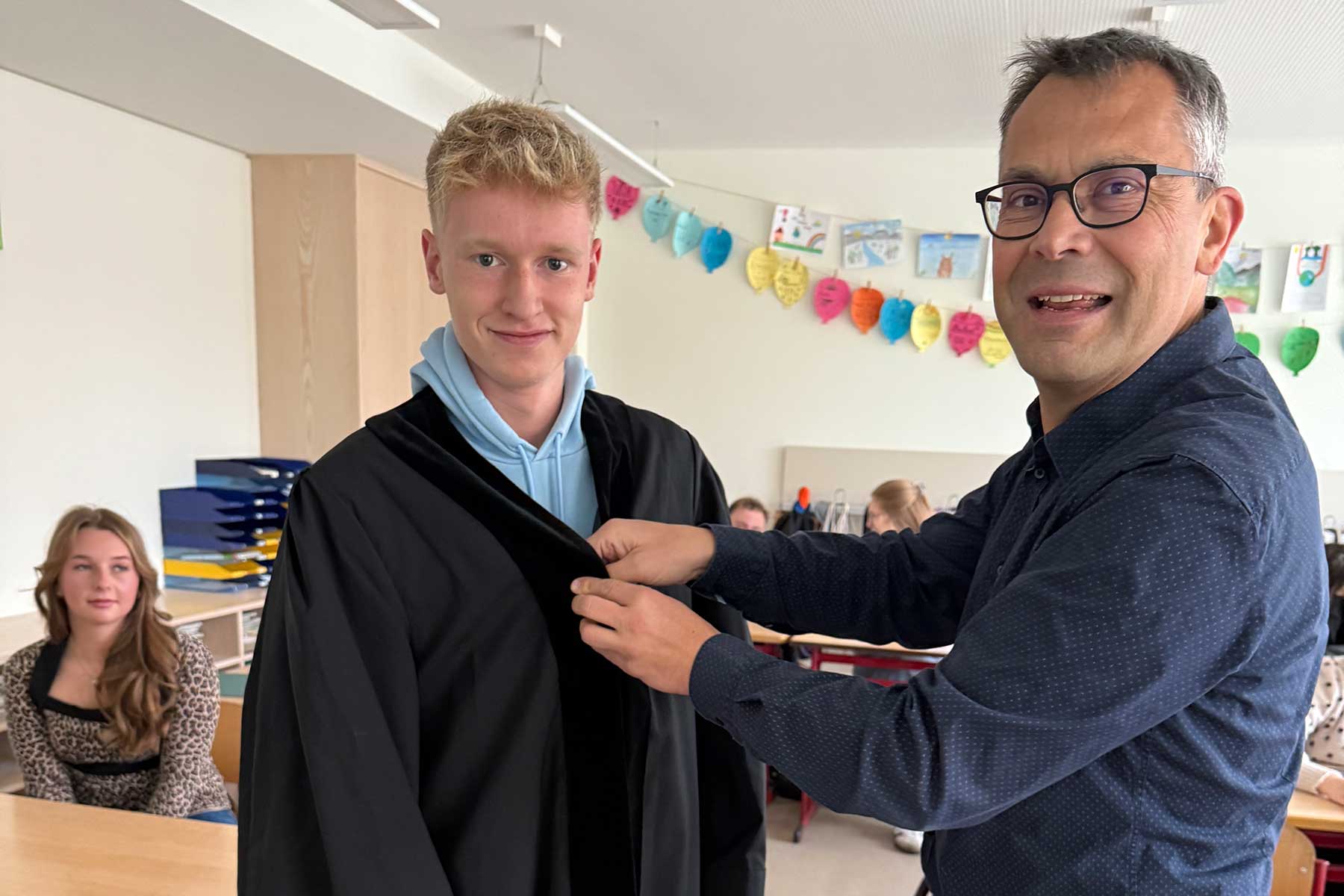 Rechtspfleger Bernhard Fiehl lässt den Schüler Jan Philipp Unterecker in die Amtsrobe schlüpfen