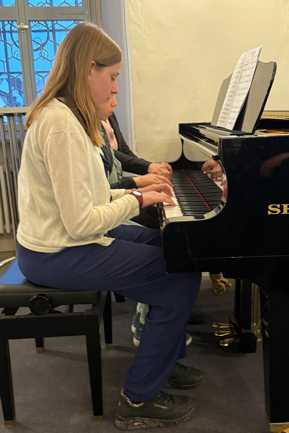 Drei Mädchen sitzen nebeneinander und spielen Klavier