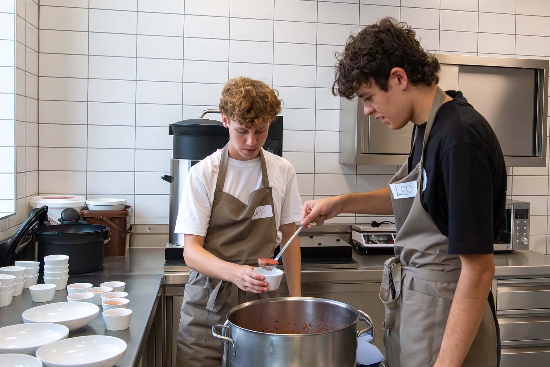 Zwei Schüler füllen Suppe in kleine Suppentassen