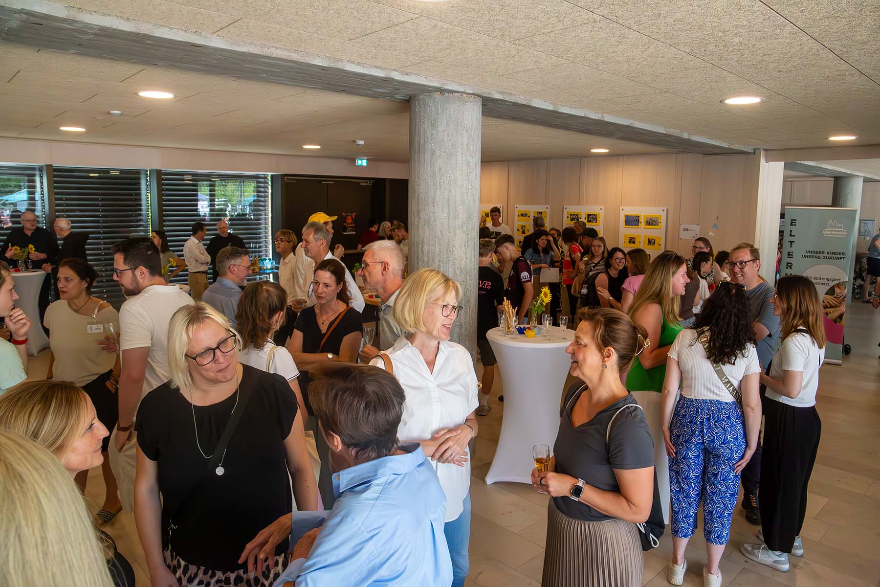 Viele Menschen stehen in kleineren Gruppen im Schulfoyer