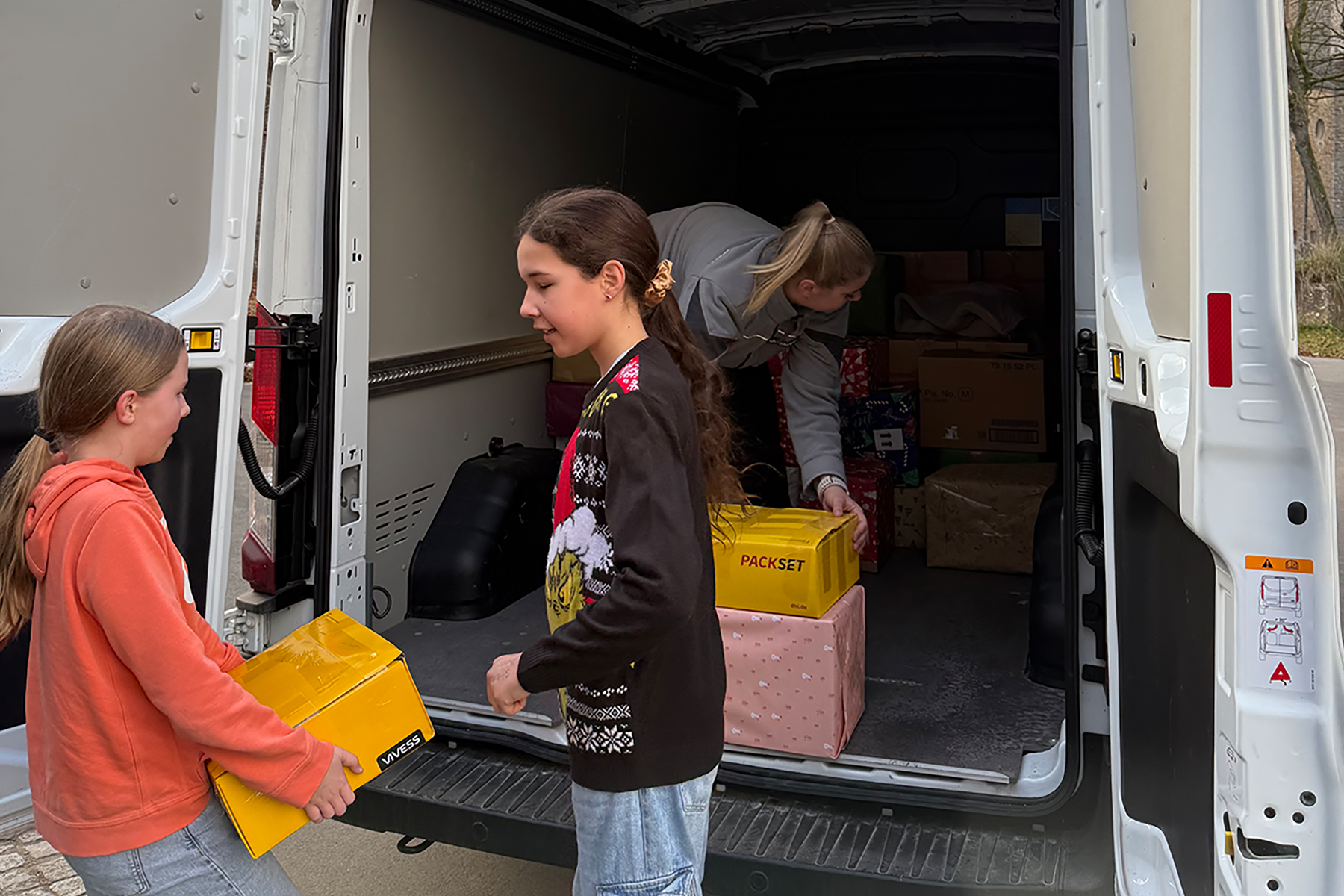 Schülerinnen beladen Fahrzeug mit Paketen