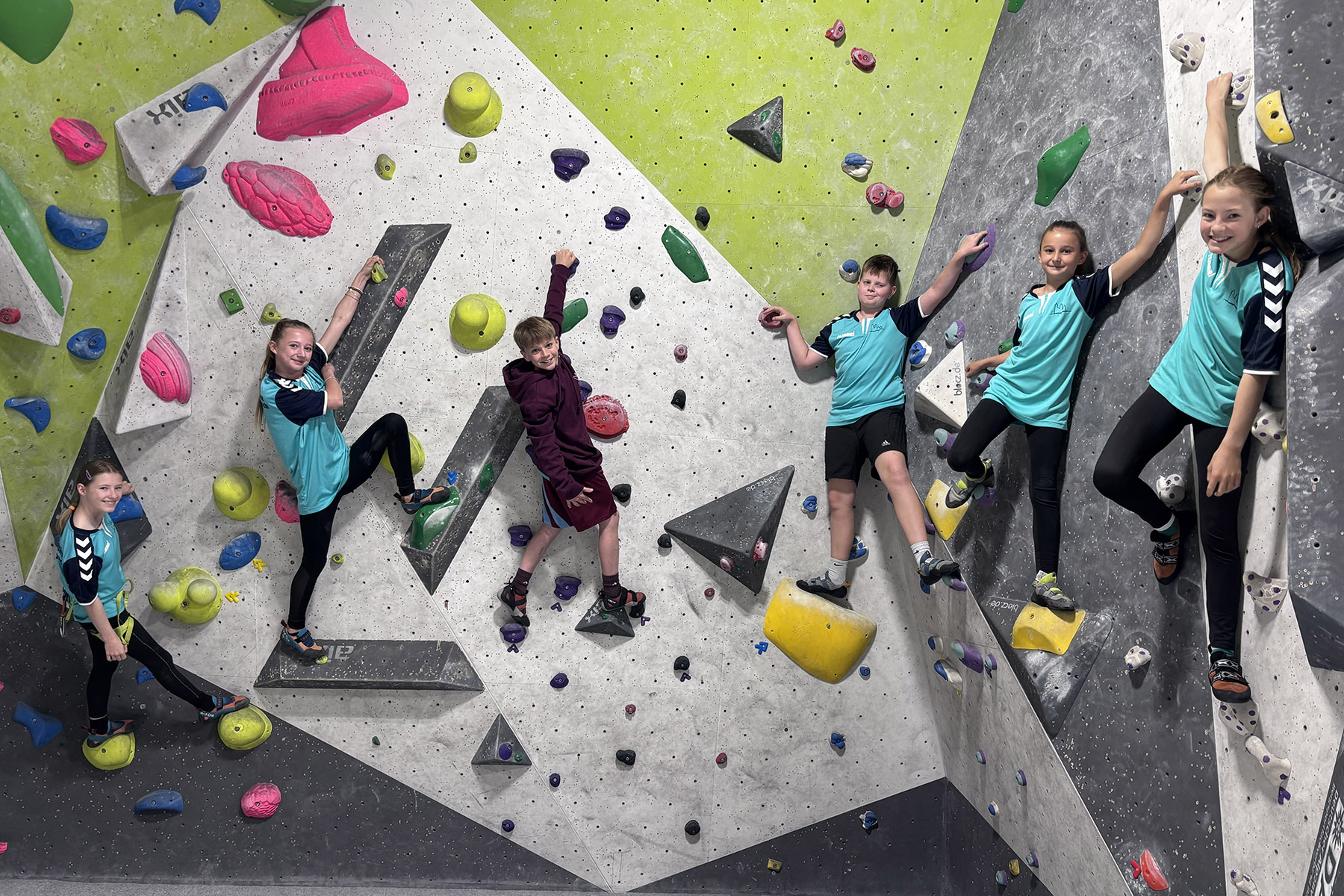 Vier Mädchen und zwei Jungen an einer bunten Kletterwand