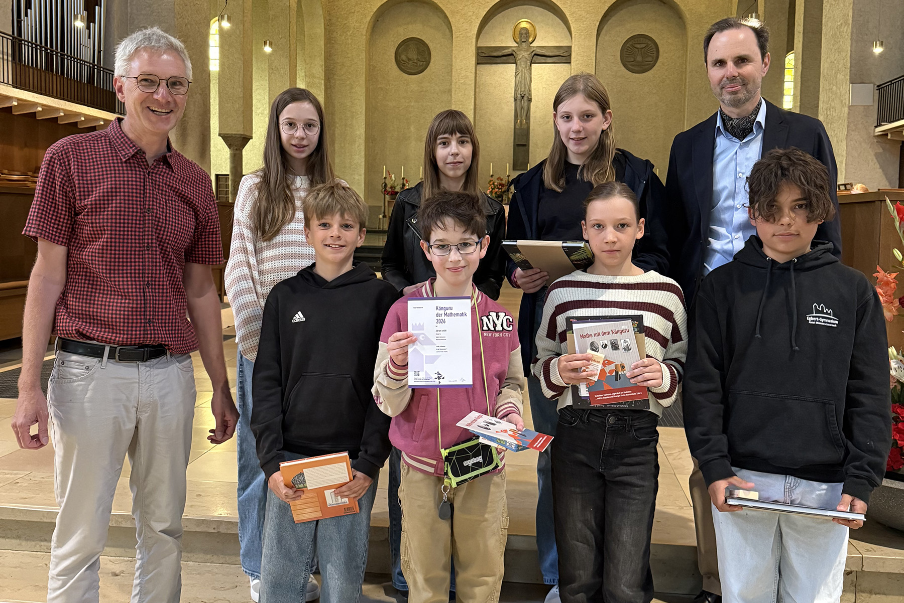 Gruppenfoto in einer Kirche, sieben Schülerinnen und Schüler mit Lehrer auf der linken und Schulleiter auf der rechten Seite