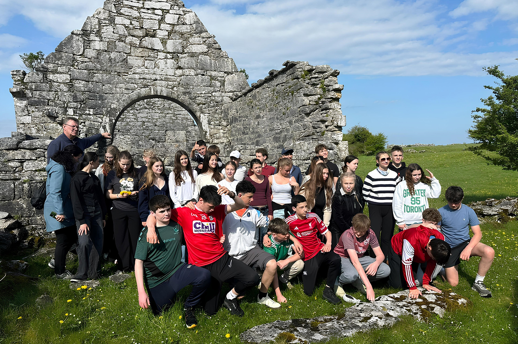 Gruppenfoto mit Schülerinnen und Schülern vor einer Ruine in einer grünen Wiese