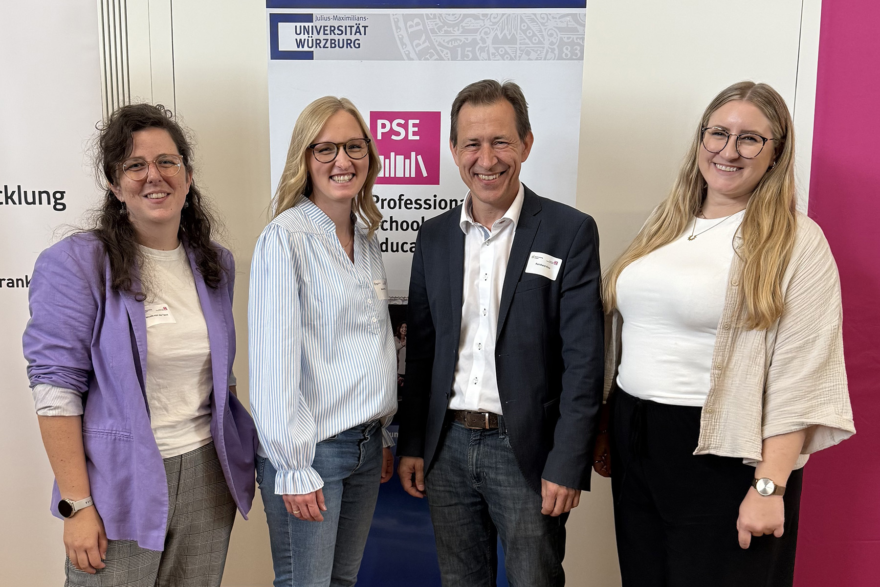 Drei Frauen und ein Mann stehen vor einem Banner
