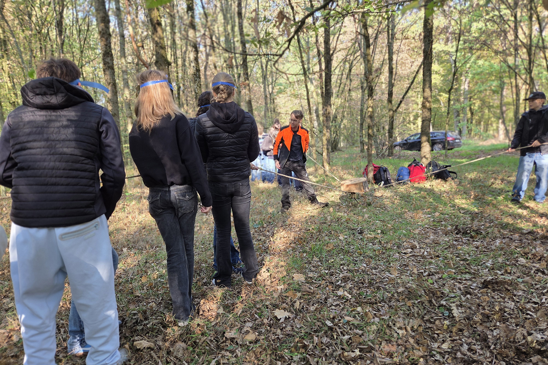Schülerinnen und Schüler mit Schutzmasken transportieren eine Baumscheibe im Wald