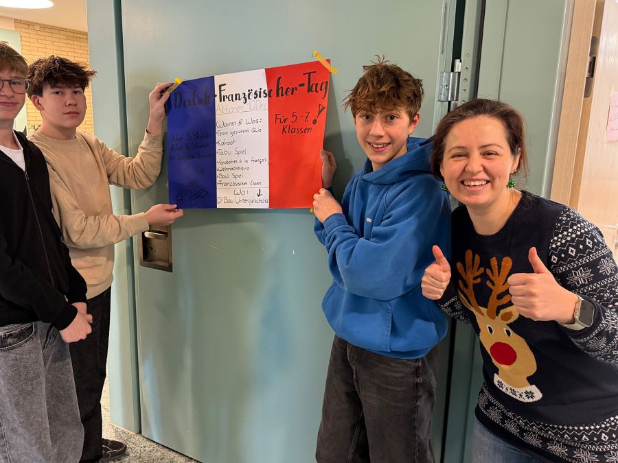 Drei Schüler halten die französische Flagge, die Lehrerin macht die Daumen nach oben
