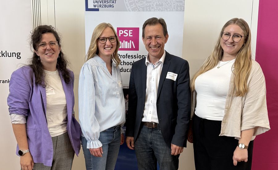 Drei Frauen und ein Mann stehen vor einem Banner