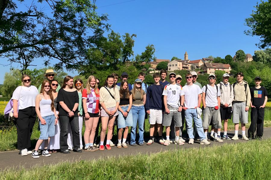 Gruppenfoto von Schülerinnen und Schülern in der Natur vor blauem Himmel