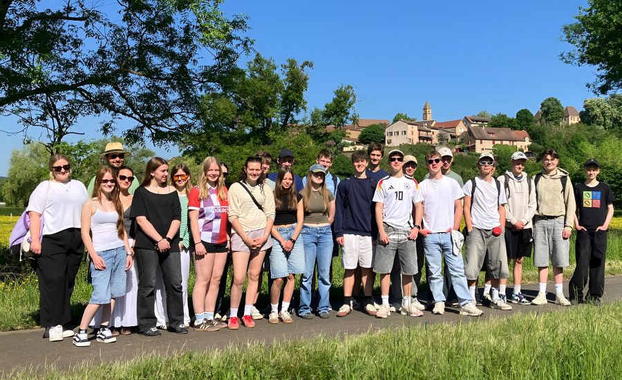 Gruppenfoto von Schülerinnen und Schülern in der Natur vor blauem Himmel