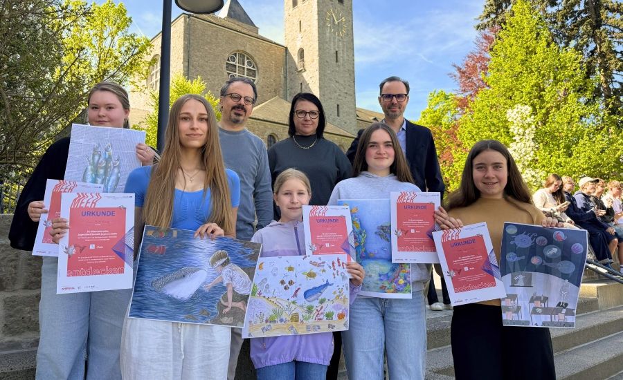 Gruppenfoto mit Abteikirche im Hintergrund: Preisträgerinnen, Schulleiter sowie Kunstlehrerin und Kunstlehrer