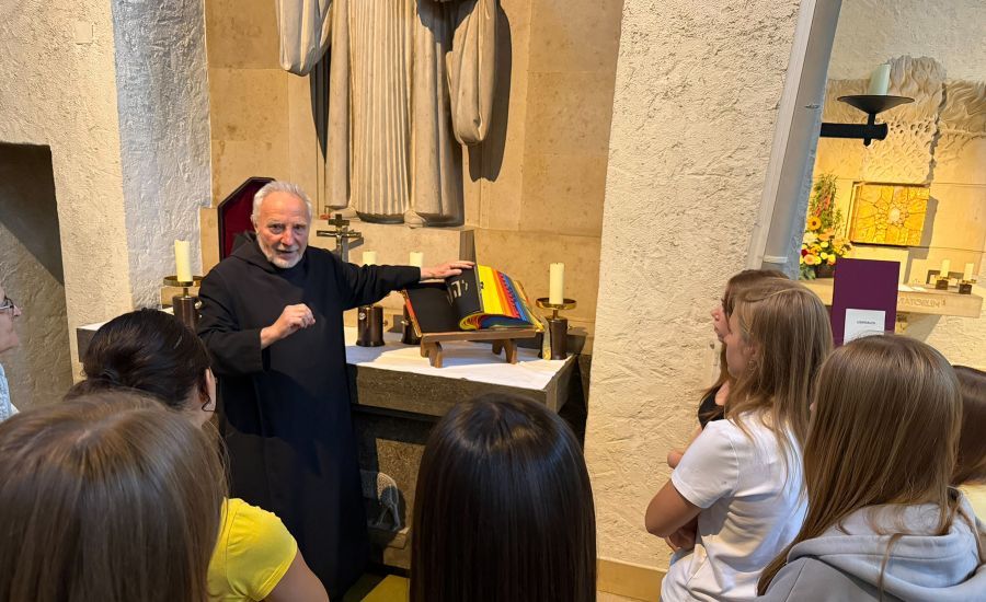 Mönch an einem Altar in der Kirche, er blättert durch ein Buch mit bunten Seiten