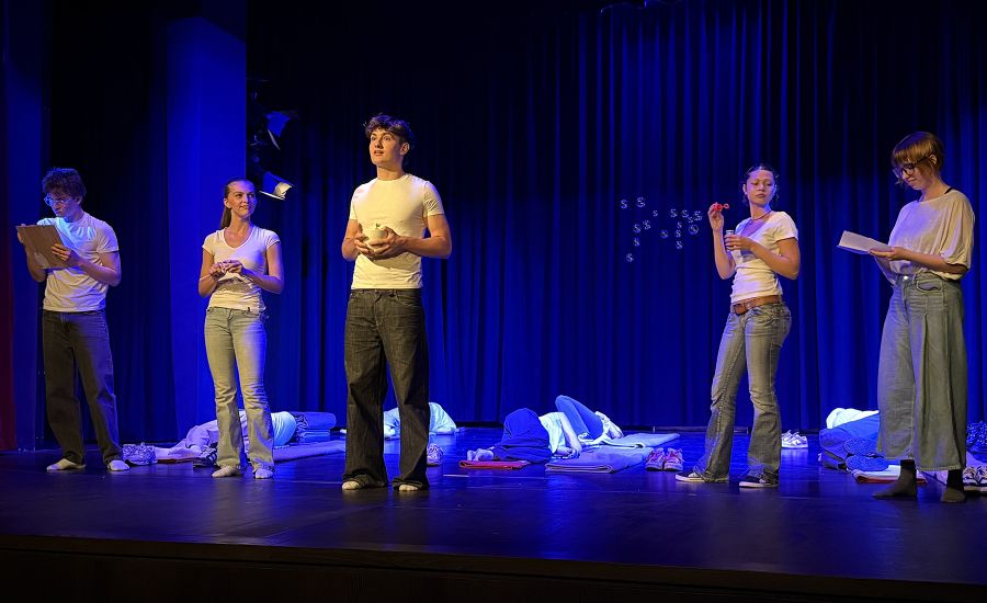 Schülerinnen und Schüler auf der im blauen Licht getauchten Theaterbühne