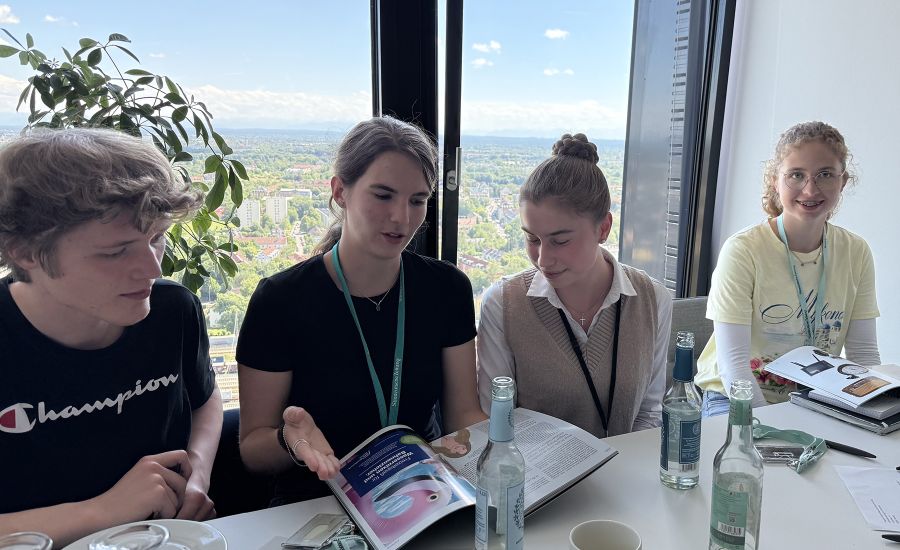 Drei Schülerinnen und ein Schüler blättern durch ein Magazin