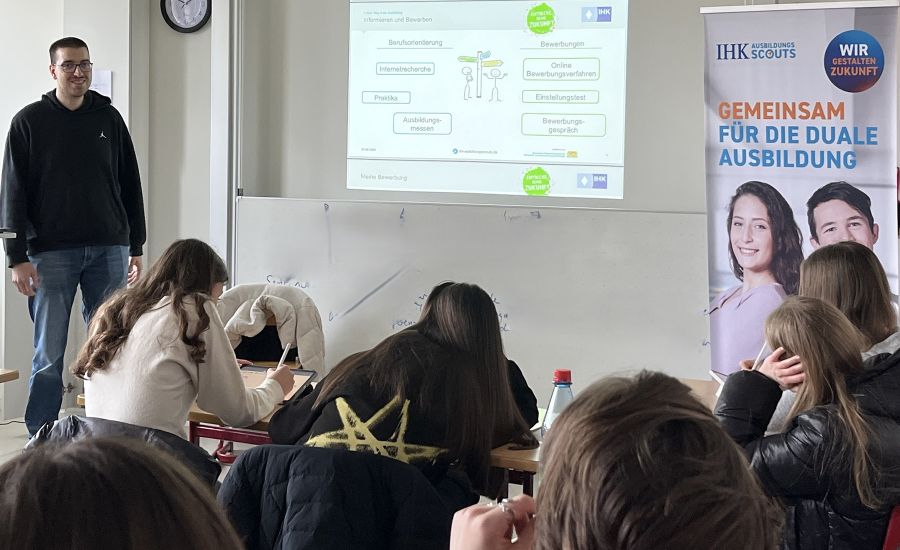 Mann steht an der Tafel vor einer Schulklasse