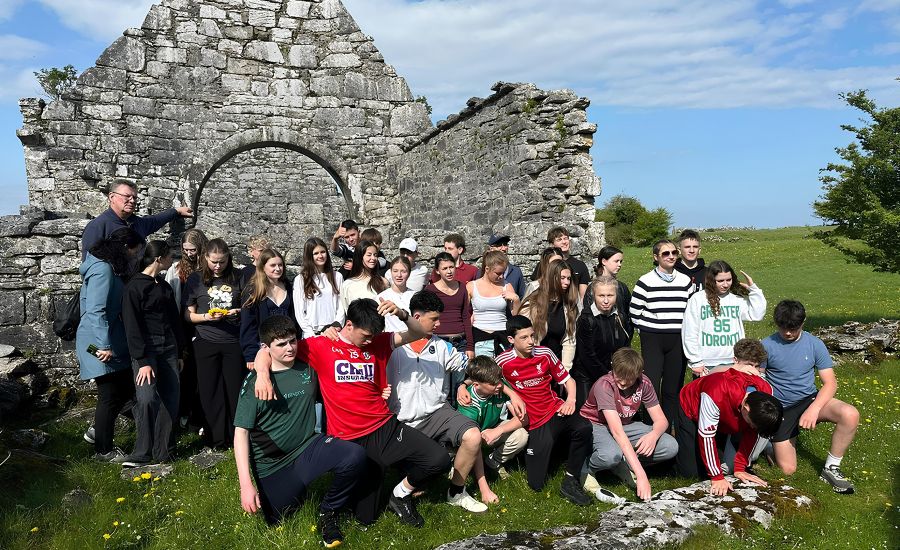 Gruppenfoto mit Schülerinnen und Schülern vor einer Ruine in einer grünen Wiese