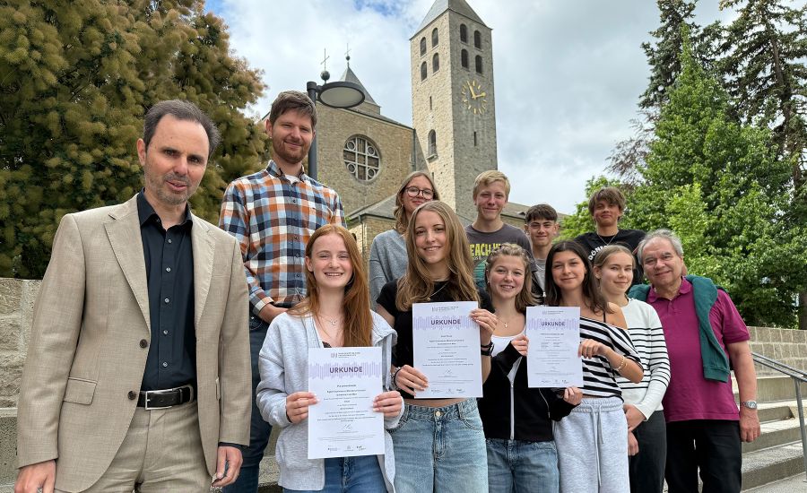 Gruppenfoto mit Schülerinnen und Schülern sowie dem Schulleiter vor einer Kirche