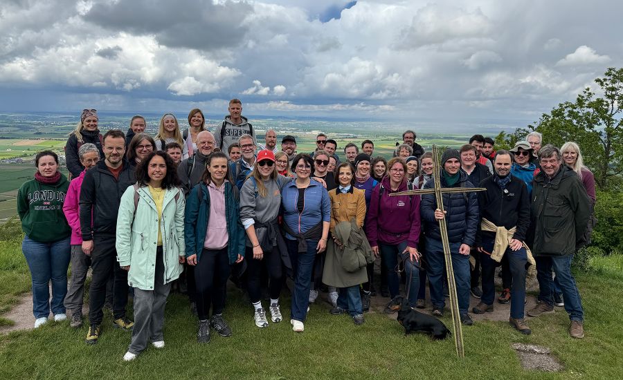 Große Gruppe von Menschen auf einer Wiese vor einem Himmel mit dichten Wolken