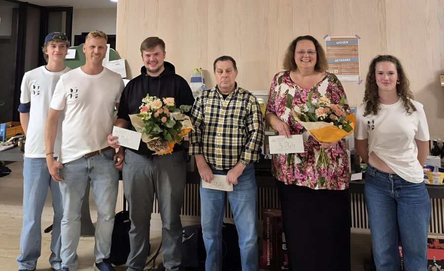 Gruppenfoto mit vier Männern und zwei Frauen, ein Mann und eine Frau halten einen Blumenstrauß