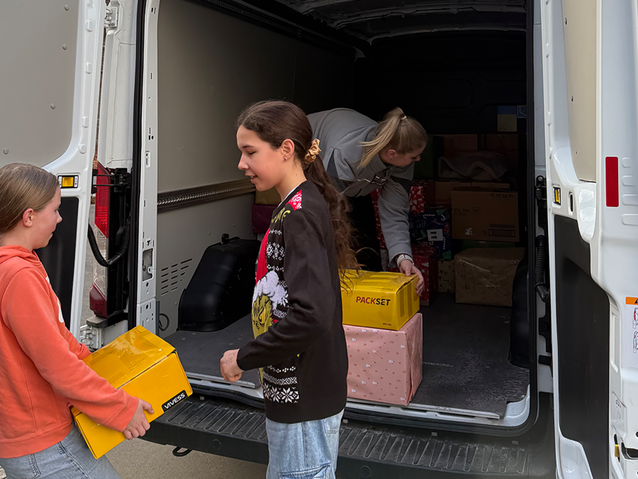 Schülerinnen beladen Fahrzeug mit Paketen