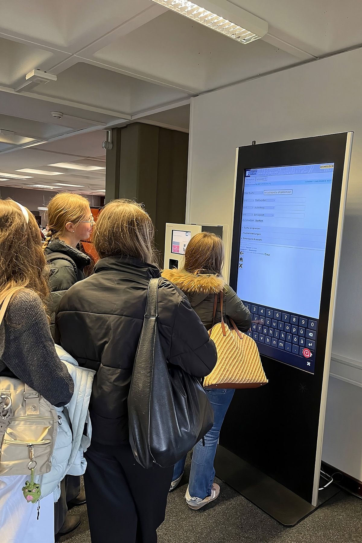 Schülerinnen vor einem Infoterminal in der Universitätsbibliothek