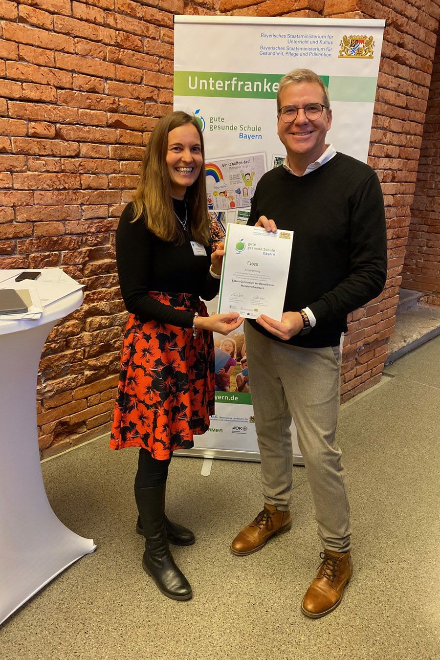 Projekt-Koordinatorin für Unterfranken, Petra Fackelmann, freut sich mit dem Vertreter des Egbert-Gymnasiums Münsterschwarzach über die Auszeichnung