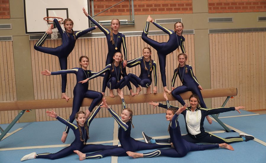 Gruppenbild der Mitglieder des Turnteams vor dem Schwebebalken