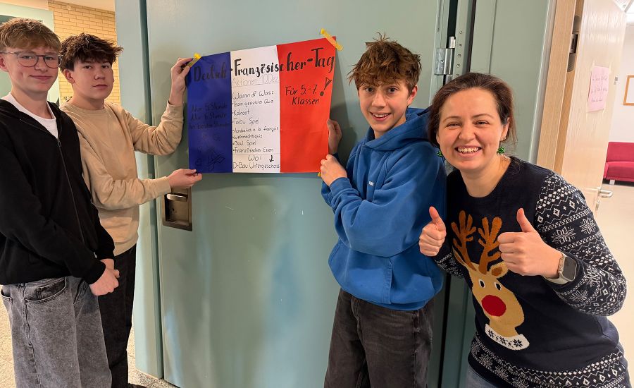 Drei Schüler halten die französische Flagge, die Lehrerin macht die Daumen nach oben